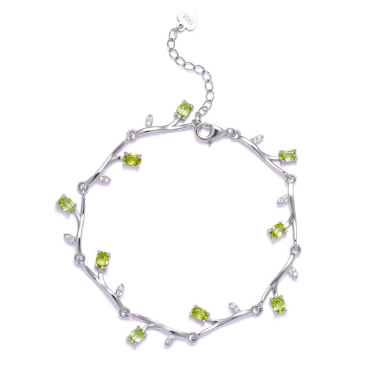 Flat lay product shot of the Awakened Time Willow Vine Signature Design bracelet featuring green peridot stones and delicate vine-inspired silver links with an extender chain.