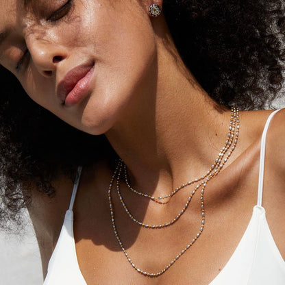 Model wearing layered Bare Luxe Éclat two-tone fine chain necklaces
