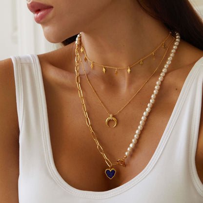 Model wearing the Venus Drip gold necklace layered with a pearl strand and pendant chain
