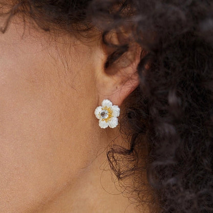 Close-up of a model wearing the silver and blue topaz Bleu de Jardin flower stud earring.