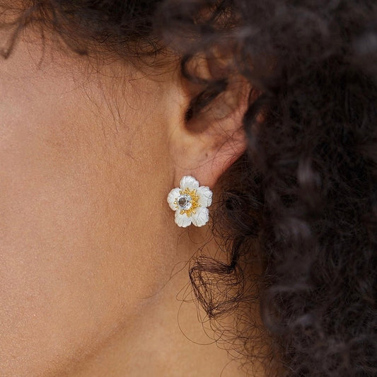Close-up of a model wearing the silver and blue topaz Bleu de Jardin flower stud earring.