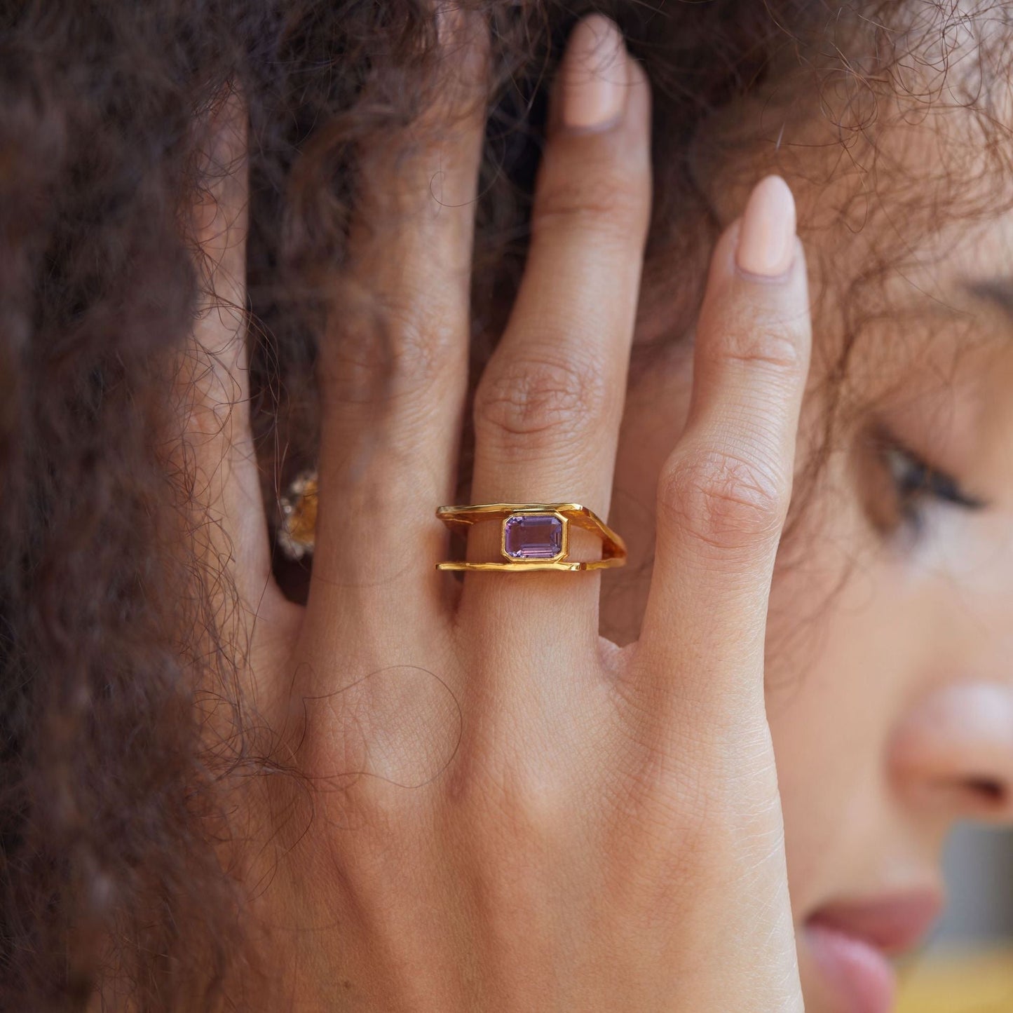 Woman wearing the Cadre de Violette 18k gold vermeil amethyst ring on her index finger in a natural lifestyle setting.