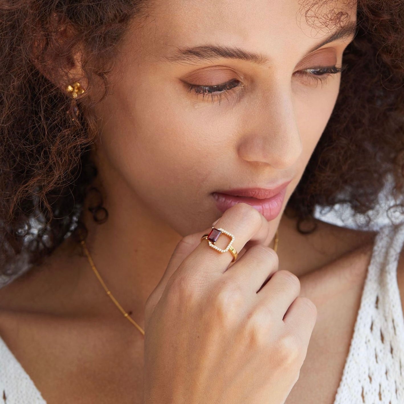 Woman wearing the Carré Rouge Garnet Ring by Awakened Time, featuring a natural red garnet gemstone and elegant 18ct gold vermeil design.