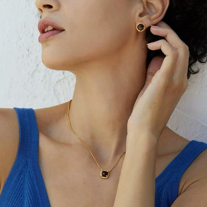 Hot and Beaufiful Model wearing a blue top posing with her hand near her neck, showcasing the Cocoa Luxe stud earrings and matching pendant necklace.
