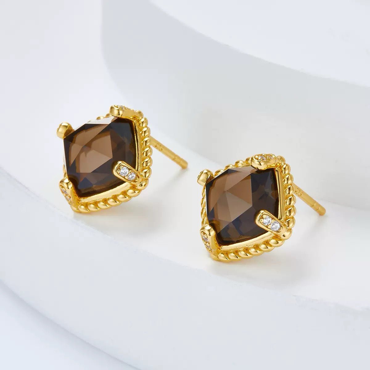 Angled view of Cocoa Luxe stud earrings displaying the cushion-cut smoky quartz gem and gold earring post.