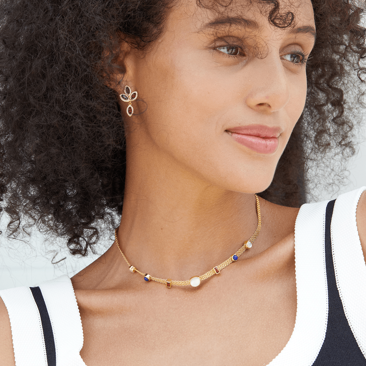 Model wearing the Fleur de Feu garnet drop earrings paired with a matching gold gemstone choker necklace.