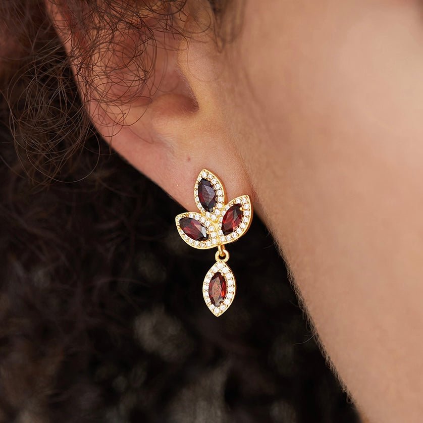 Close-up of a model wearing the Fleur de Feu red garnet and gold leaf drop earring.