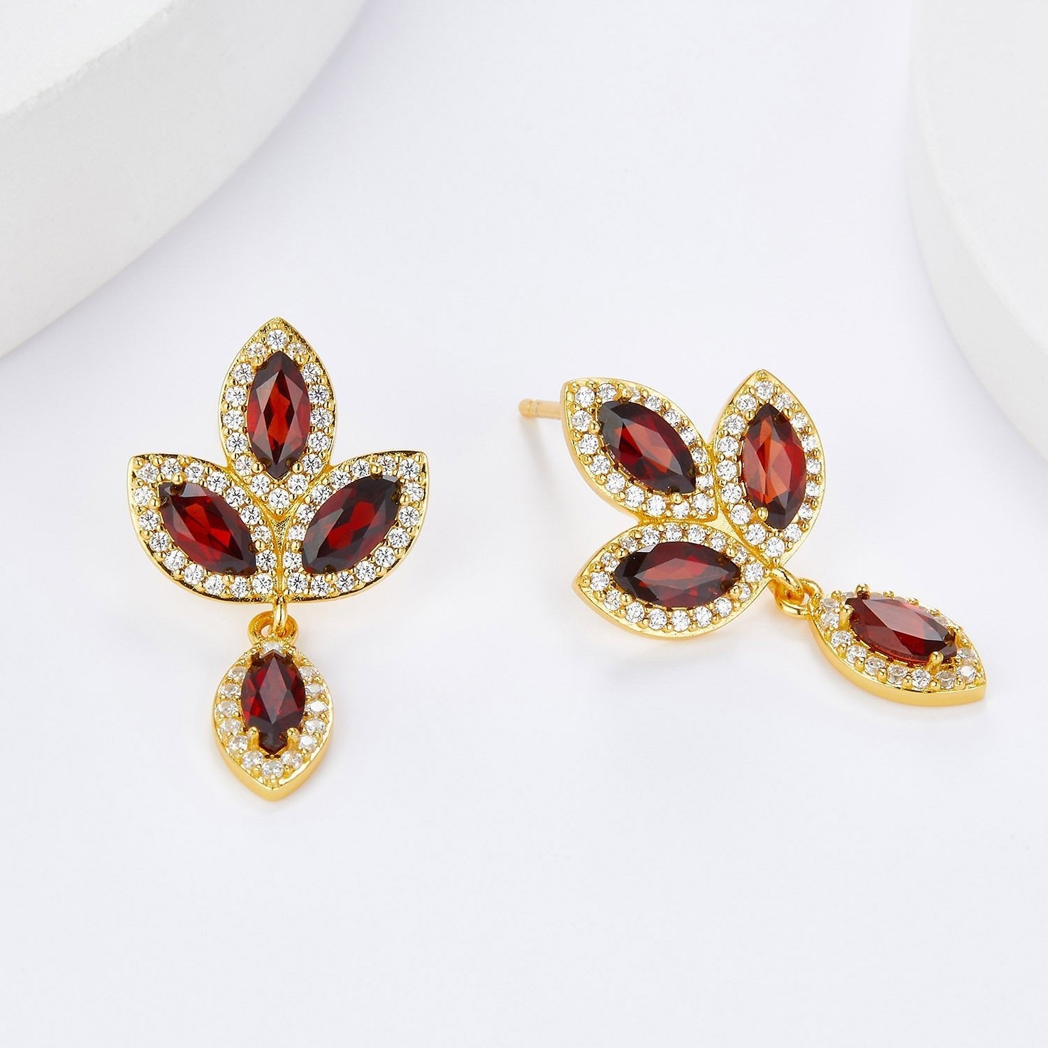 Front and side view of the Fleur de Feu gold drop earrings displaying the stud post backing and dangling marquise garnet charm.