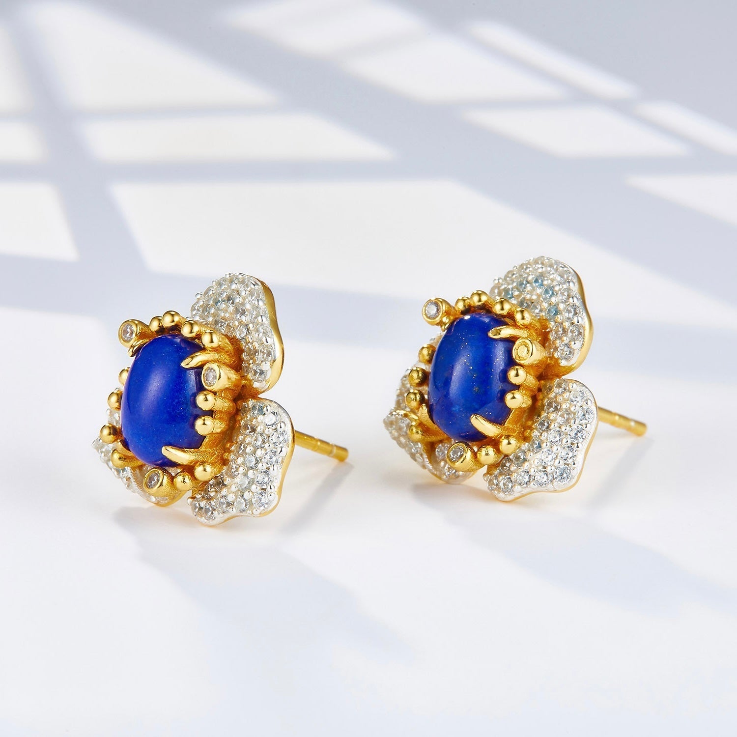 Angled view of the Fleur d’Écume lapis lazuli earrings highlighting the raised prongs and sculptural gold design.