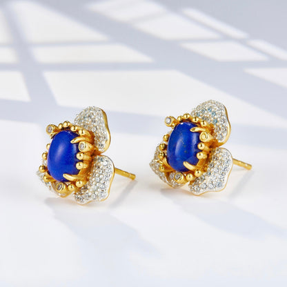 Angled view of the Fleur d’Écume lapis lazuli earrings highlighting the raised prongs and sculptural gold design.