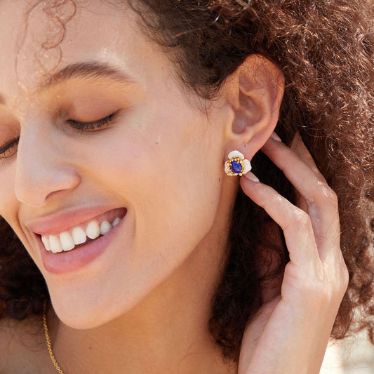 Model smiling while wearing the Fleur d’Écume blue lapis lazuli stud earring featuring pavé zirconia floral petals.