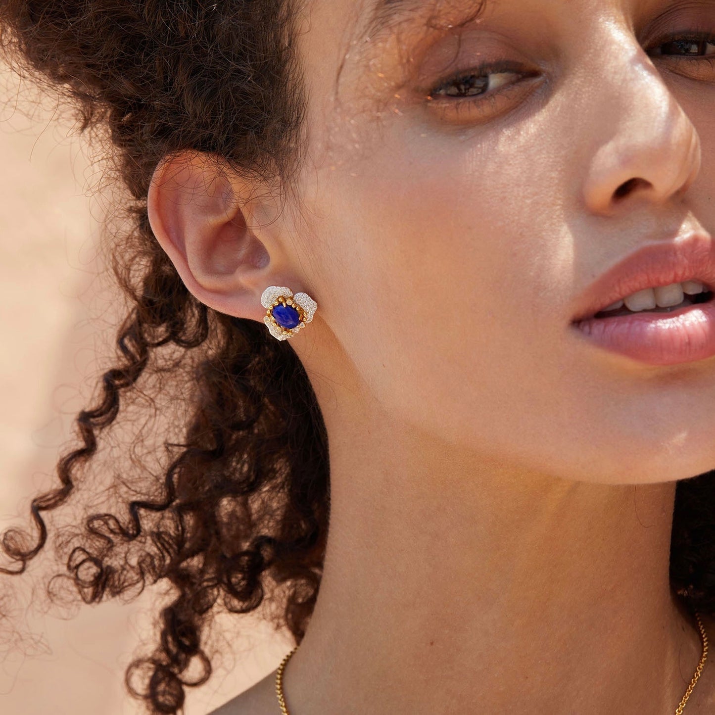 Side profile of a model showcasing the vibrant blue lapis lazuli and gold Fleur d’Écume stud earring.