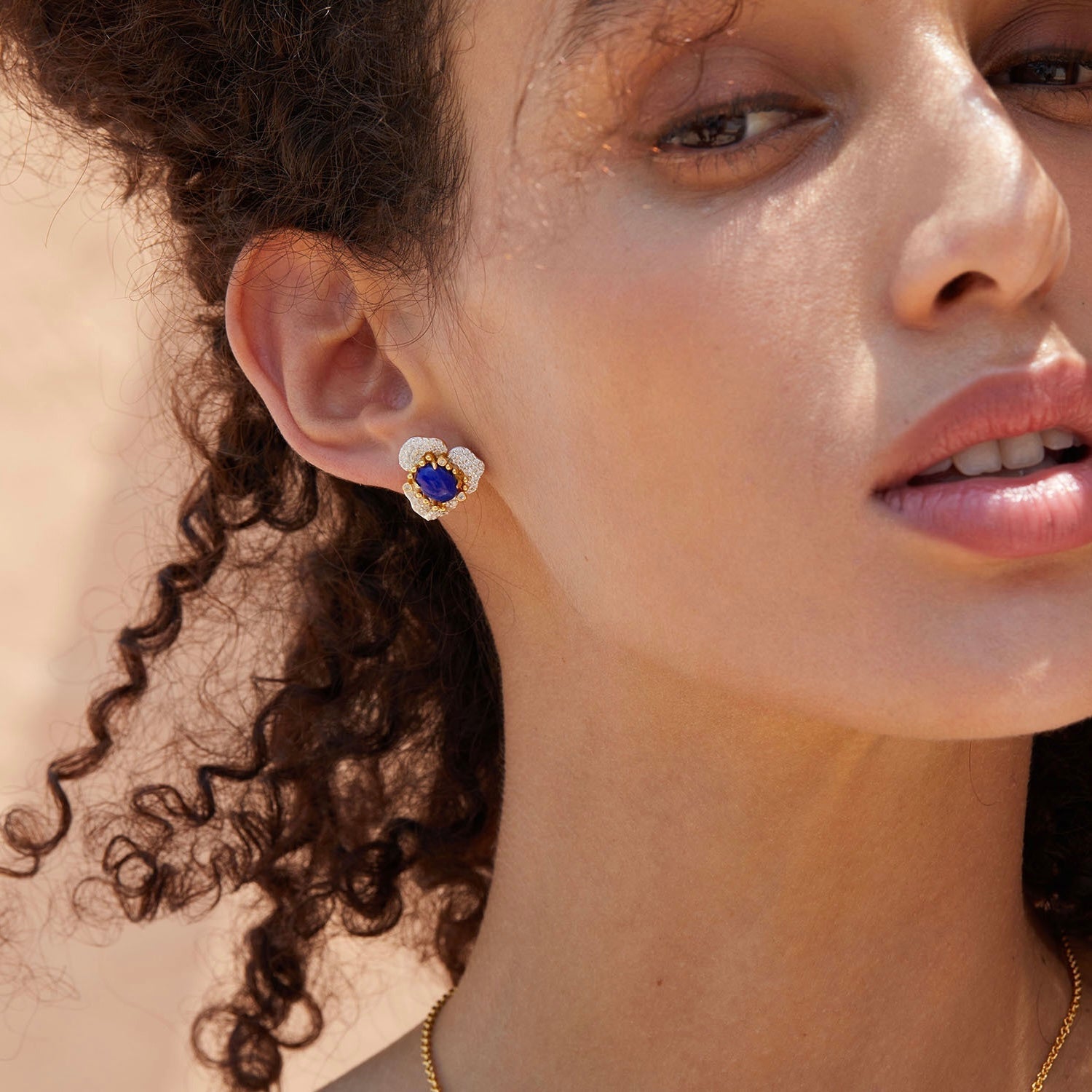 Side profile of a model showcasing the vibrant blue lapis lazuli and gold Fleur d’Écume stud earring.