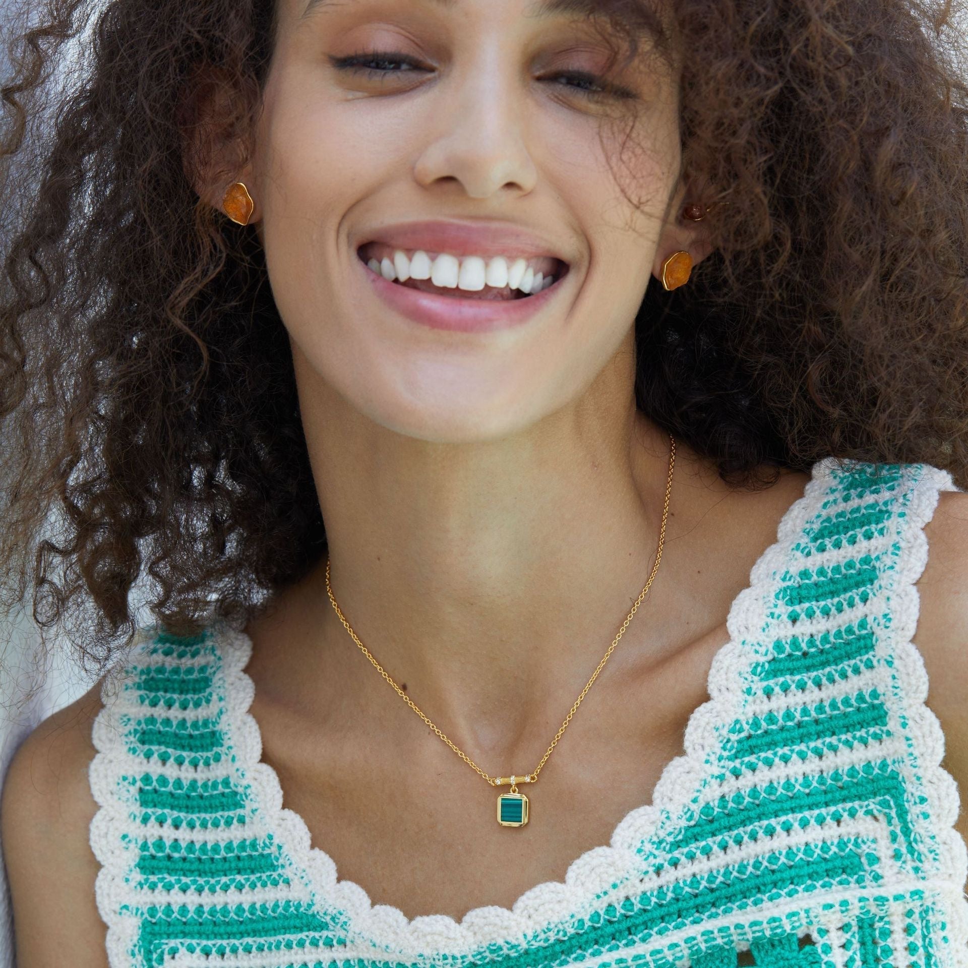Model wearing the Garden Square green malachite pendant necklace styled with a green knit top