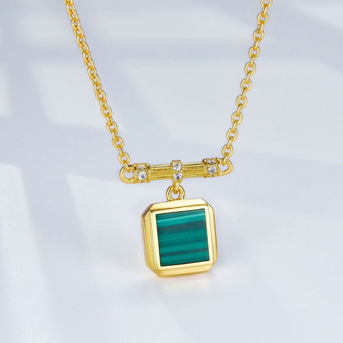 Close-up of the square malachite pendant suspended from a pave-set gold bar