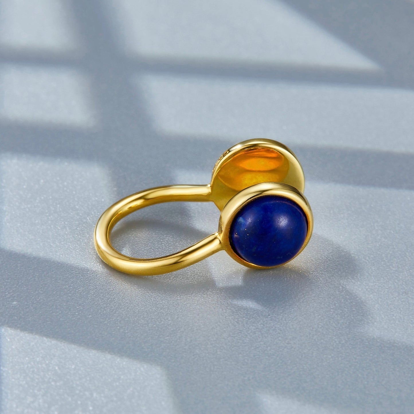 Close-up studio shot of the Gemini gold ear cuff resting on a surface, focusing on the lapis lazuli cabochon.