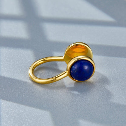 Close-up studio shot of the Gemini gold ear cuff resting on a surface, focusing on the lapis lazuli cabochon.