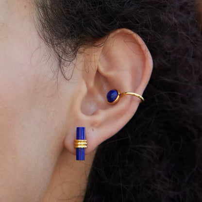 Close-up profile of a model wearing the Gemini gold ear cuff displaying the deep blue lapis lazuli stone on the conch.