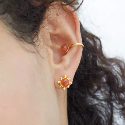 Close-up profile of a model wearing the Gemini ear cuff highlighting the warm peach sunstone gem on the upper cartilage.
