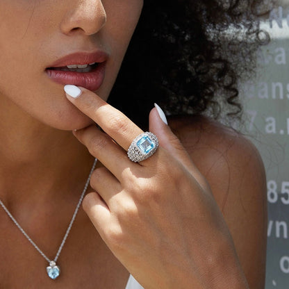 Editorial lifestyle portrait of a model wearing the Awakened Time Glacier Crown luxury statement ring with a radiant natural blue topaz stone, set in 18ct white gold vermeil and styled with a matching pendant necklace.