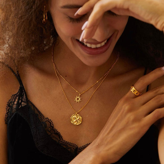 Woman wearing the gold Helia sun pendant necklace with black lace top