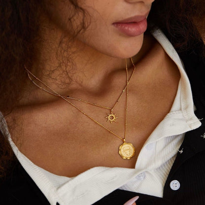 Model wearing the Helia gold sun necklace layered with a larger gold pendant before her lover came inside.