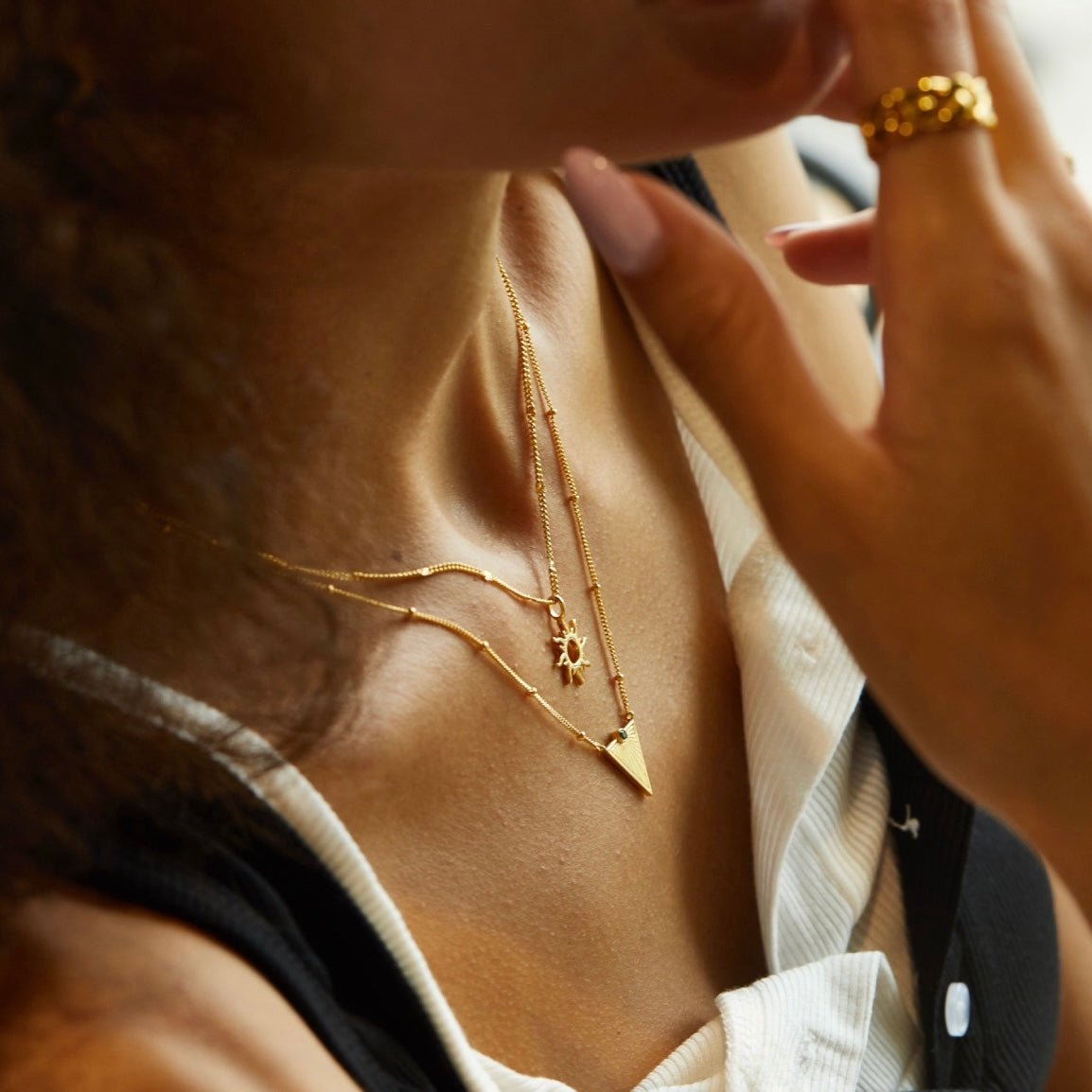Helia gold sun necklace styled with a flat gold snake chain and coin pendant