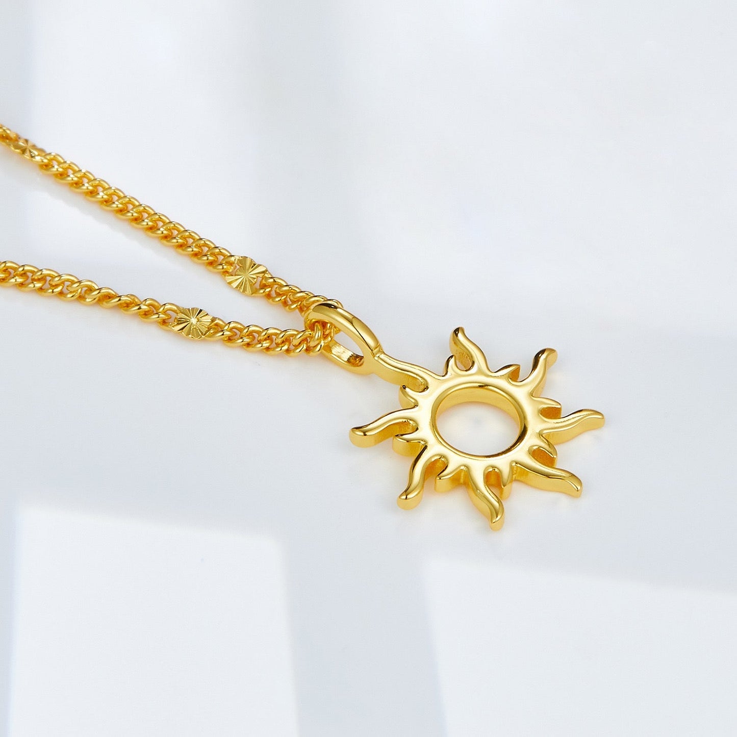 Close-up of the sunburst Helia pendant in 18ct gold vermeil on a light background