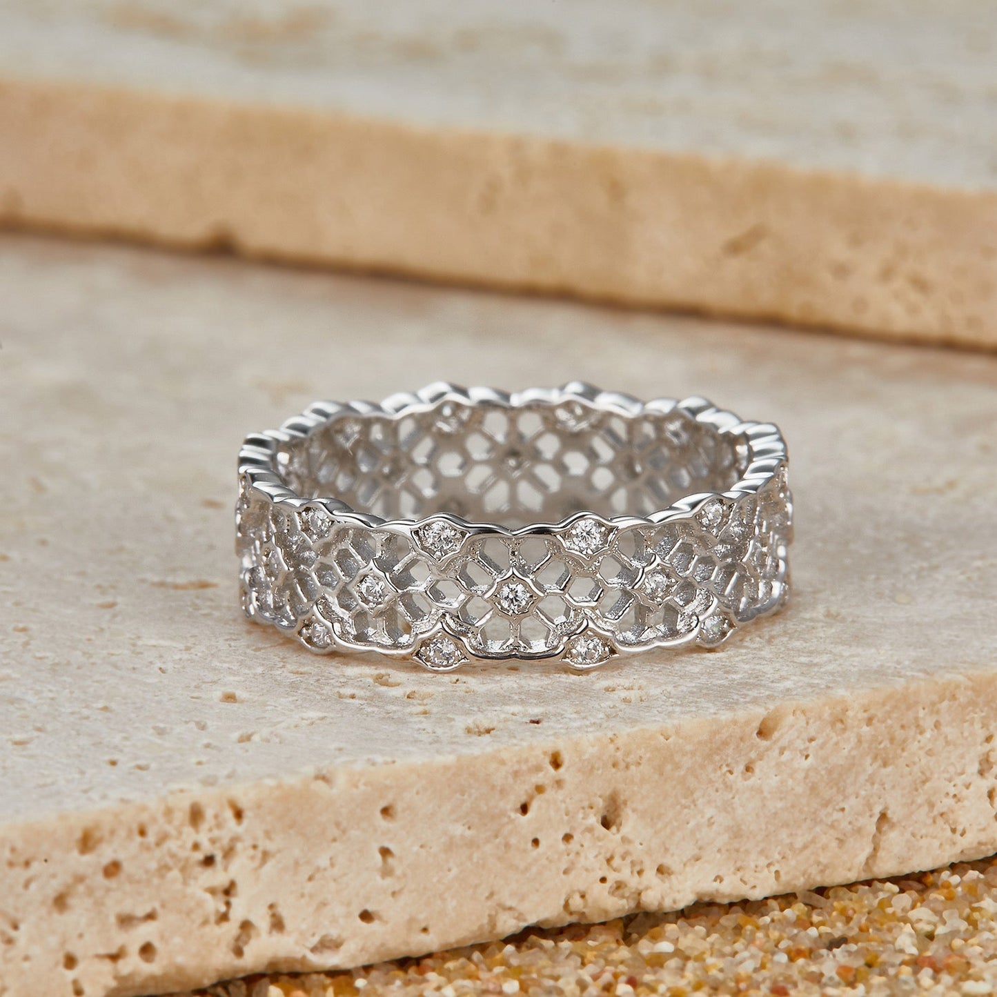 Awakened Time Iceveil Band resting on natural stone, showcasing its intricate Parisian-inspired white gold vermeil filigree pattern and sparkling cubic zirconia stones.