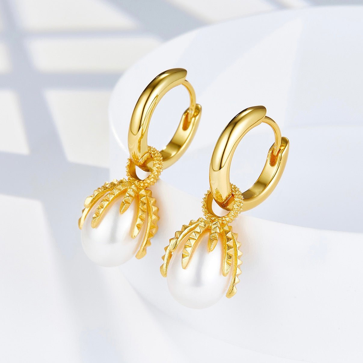 Angled view of Jardin Secret gold huggie earrings highlighting the detailed textured vine cap encircling the white freshwater pearl drops.