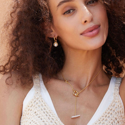 Model wearing the Jardin Secret gold pearl drop earrings paired with a matching pearl lariat necklace.