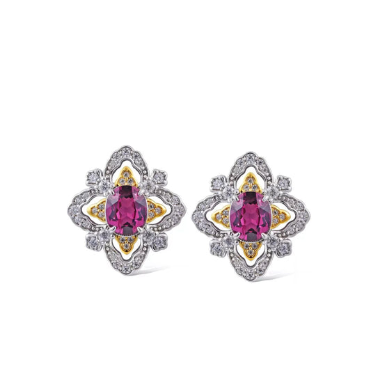 Pair of La Rosa di Firenze garnet earrings resting on a white display plate over a rich brown surface.