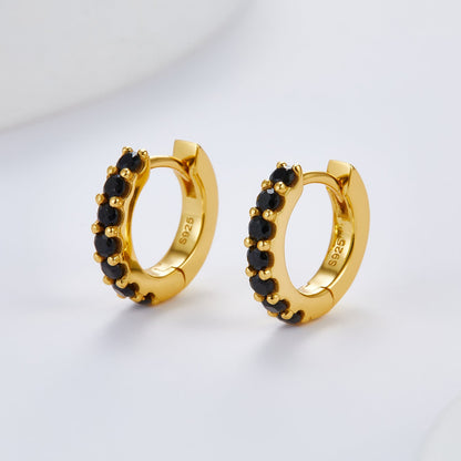 Front angle view of the Noir Éclat gold huggie hoop earrings set with micro-pavé black stones.