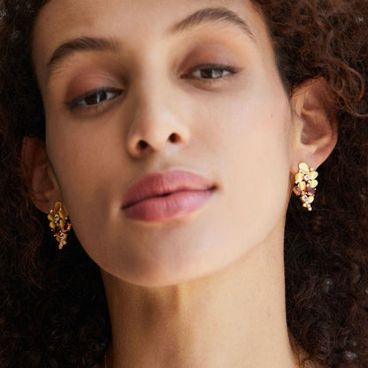 Front view portrait of a model wearing Opéra de Feu 18ct gold vermeil and red garnet earrings.