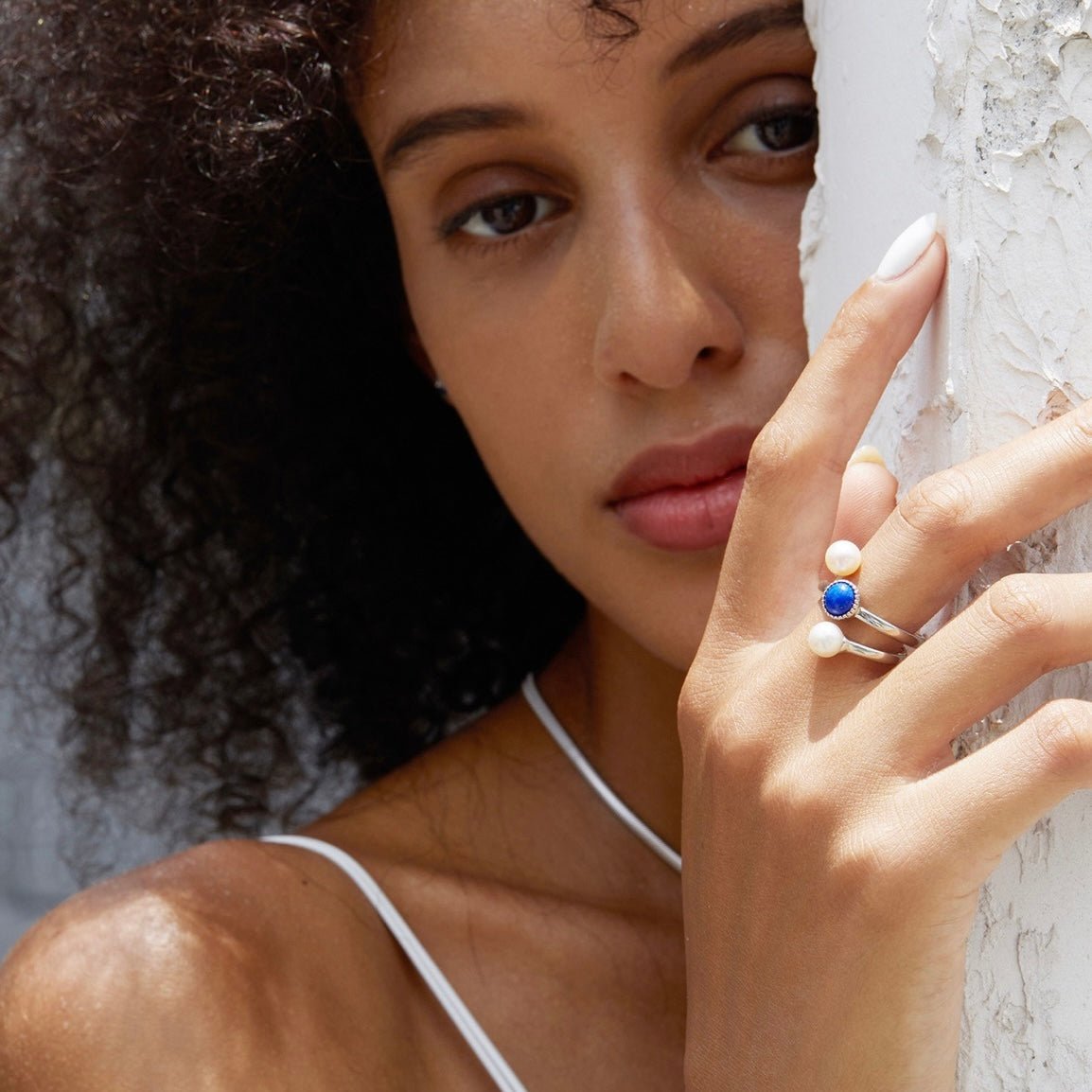Editorial lifestyle portrait of a model wearing the Awakened Time Pearl Cosmos luxury ring featuring natural deep blue lapis lazuli and freshwater pearls, set in 18ct white gold vermeil.