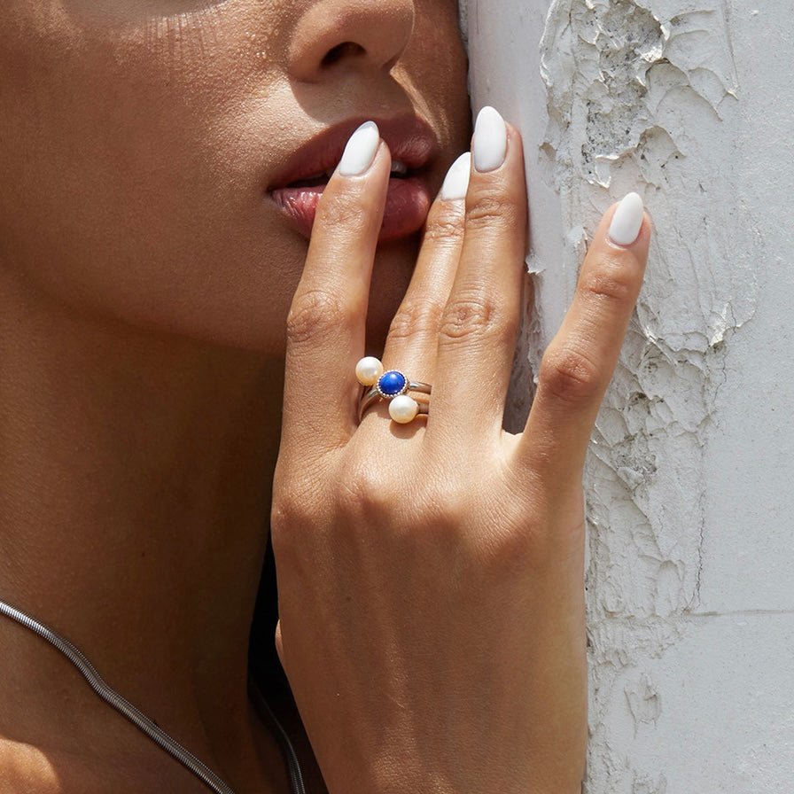 Editorial lifestyle portrait of a model wearing the Awakened Time Pearl Cosmos luxury ring featuring natural deep blue lapis lazuli and freshwater pearls, set in 18ct white gold vermeil.