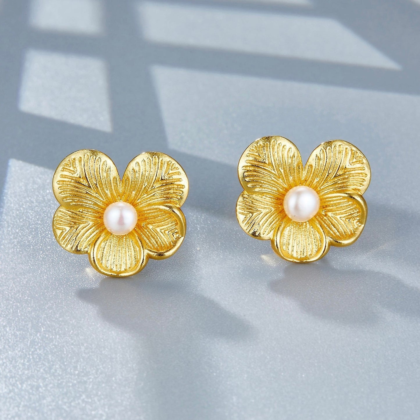 High-angle view of the gold petal pearl studs showing the textured flower petals and freshwater pearl centerpieces.