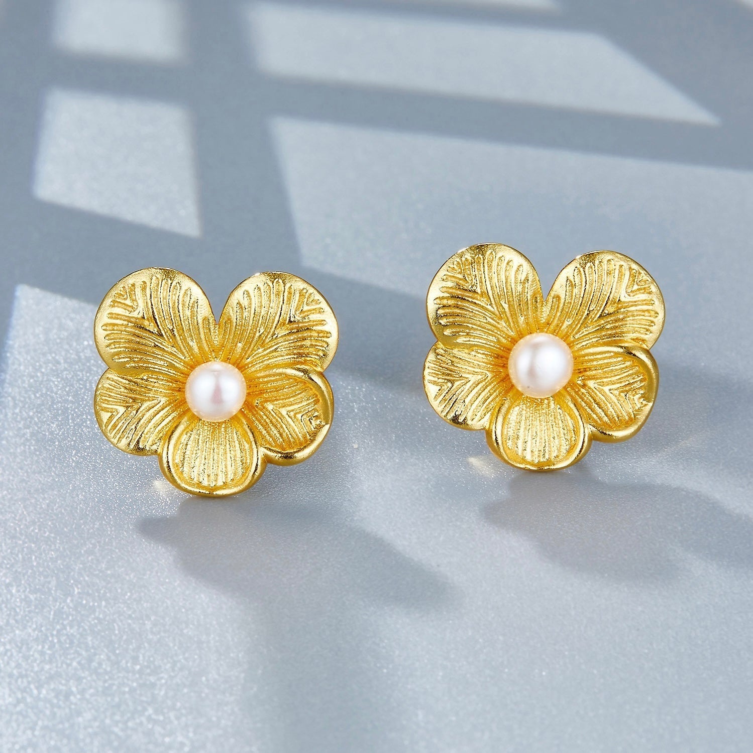 High-angle view of the gold petal pearl studs showing the textured flower petals and freshwater pearl centerpieces.