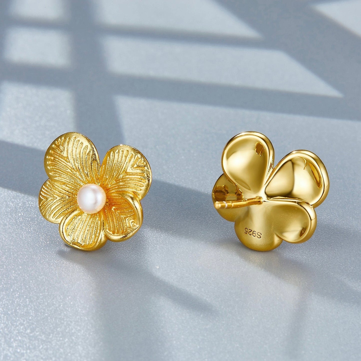 Front and back view of gold petal pearl stud earrings displaying the flower post and backing detail.