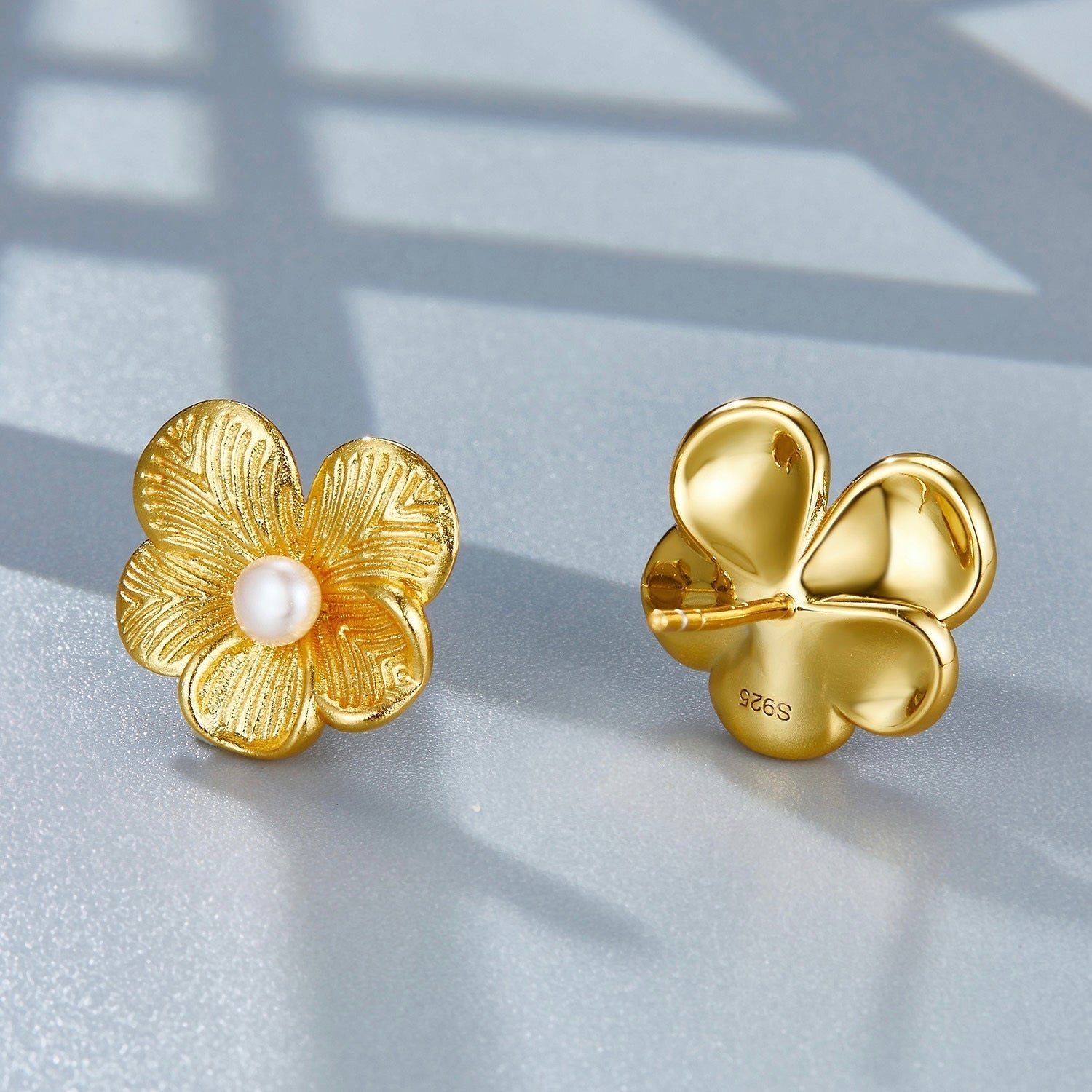 Front and back view of gold petal pearl stud earrings displaying the flower post and backing detail.