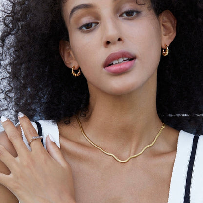 Model wearing Roma Twist gold vermeil hoop earrings styled with a gold chain necklace.