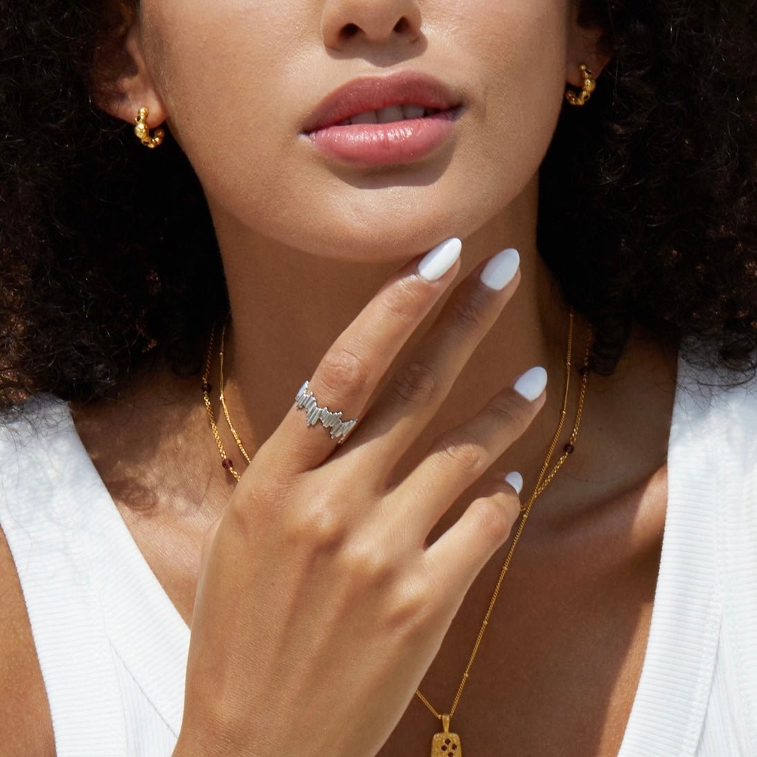 Editorial lifestyle portrait of a model wearing the Awakened Time Silver Shard Irregular luxury ring with a sculptural jagged silhouette, set in 18ct white gold vermeil and styled with complementary gold jewelry.
