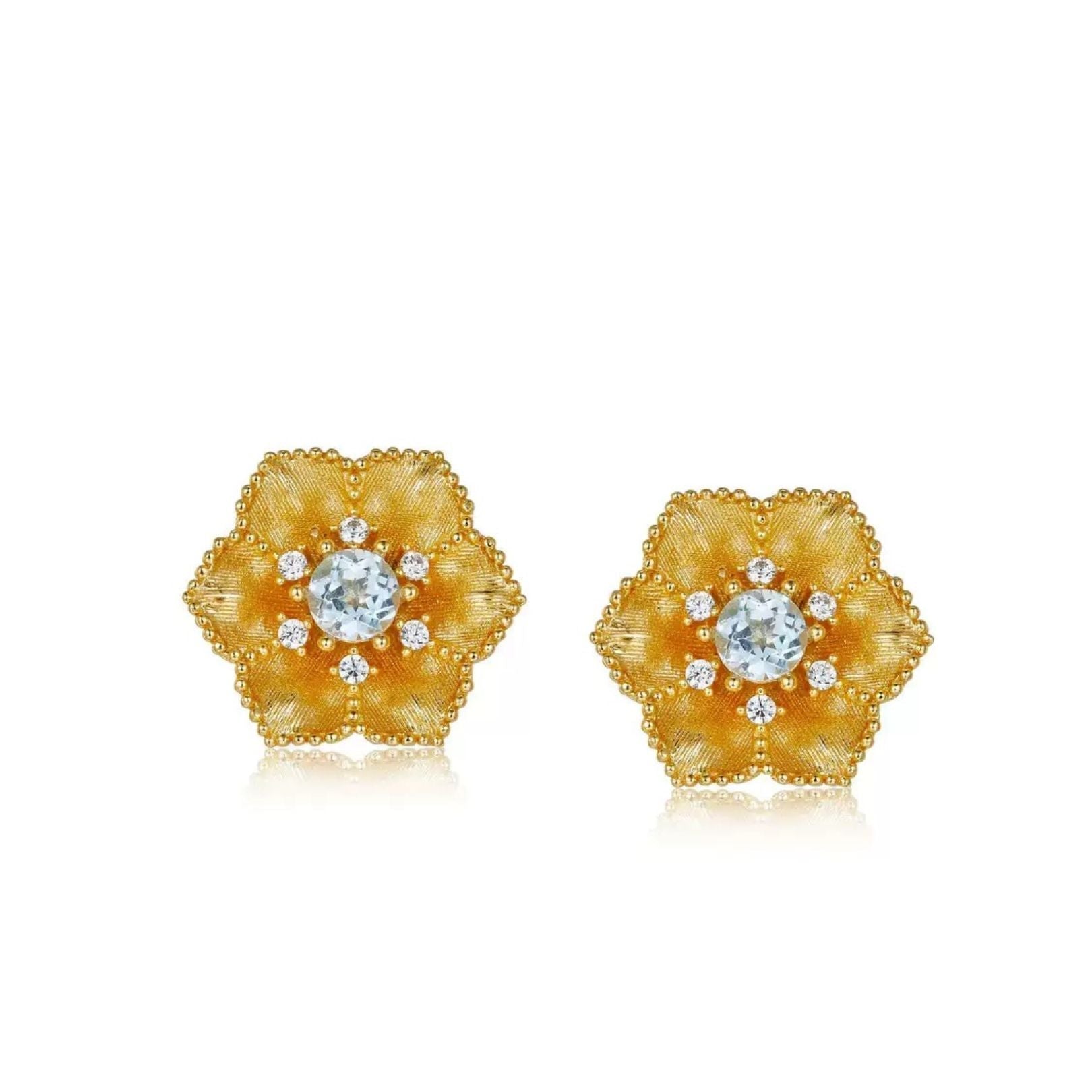 Pair of gold floral Soleia Bloom stud earrings featuring a central blue topaz stone surrounded by delicate accent gems.