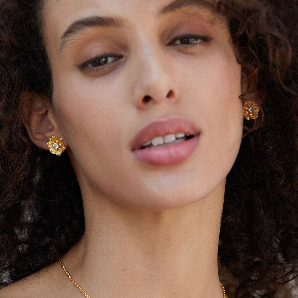 Close-up of model's profile highlighting the gold floral design of the Soleia Bloom stud earring.