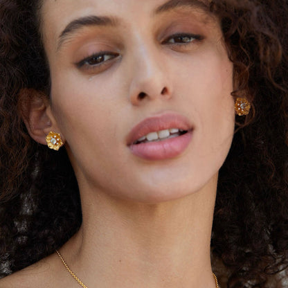 Close-up of model's profile highlighting the gold floral design of the Soleia Bloom stud earring.
