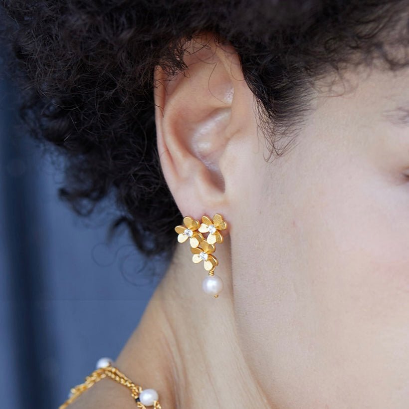 Side angle of a model showing the fit and size of the gold clover floral cluster earring.