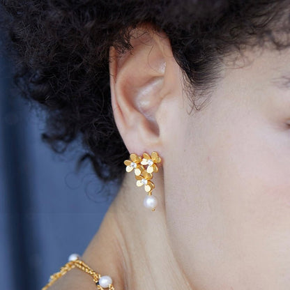 Side angle of a model showing the fit and size of the gold clover floral cluster earring.