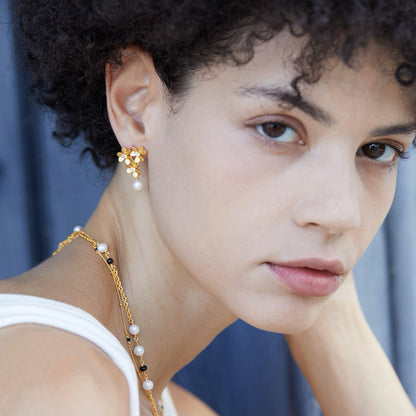 Model wearing the Trèfle d’Or gold pearl drop earrings with a matching gold pearl necklace.