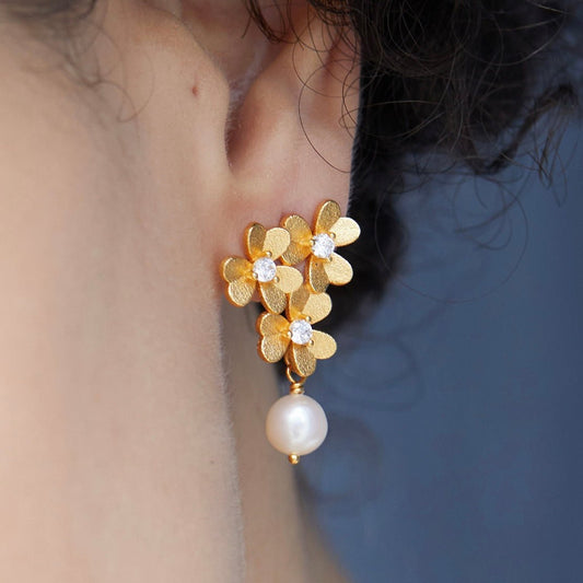 Close-up profile view of a model wearing the gold Trèfle d’Or clover earring with a pearl drop.