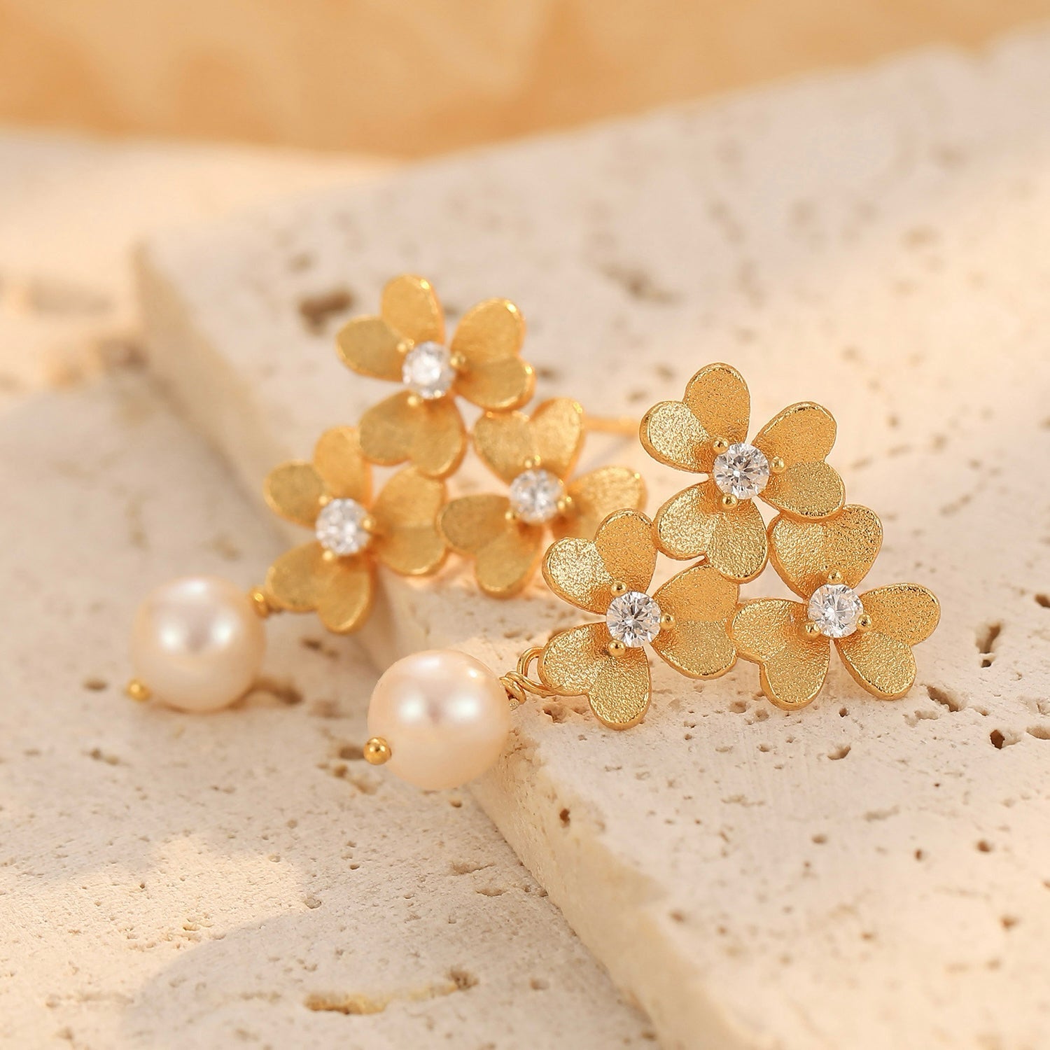Close-up of the textured gold clover petals and freshwater pearl dangling from the Trèfle d’Or earring.